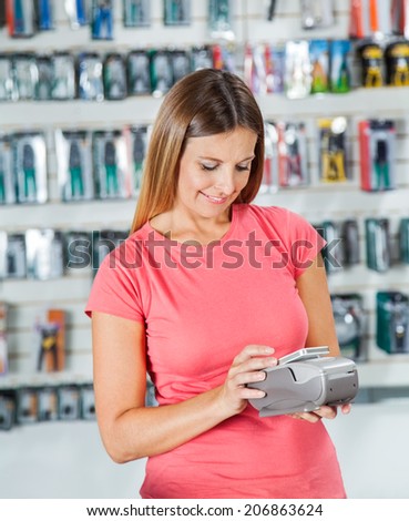 Smiling mid adult woman making payment through smartphone in hardware store