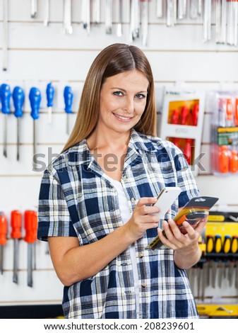 Portrait of female customer scanning product\'s barcode through mobilephone in hardware store