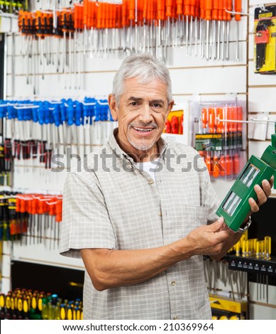 Portrait of happy senior customer holding packed product in hardware shop