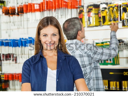 Portrait of beautiful woman smiling with man buying tools in background at hardware store