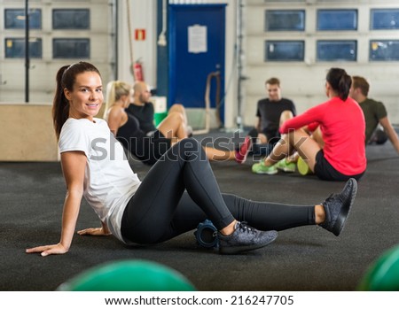 Full length portrait of young woman exercising in cross fitness box