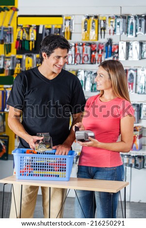 Smiling couple looking at each other while paying through credit card in hardware store