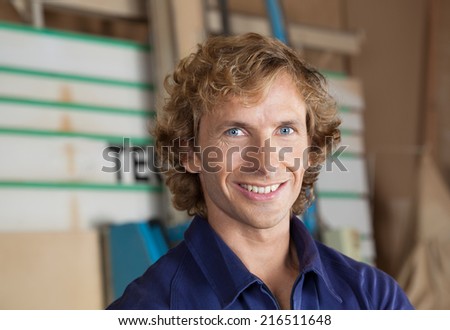 Close-up portrait of confident carpenter smiling in workshop