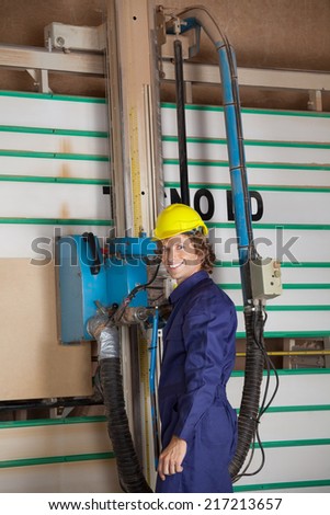 Portrait of confident carpenter using vertical saw machine in workshop