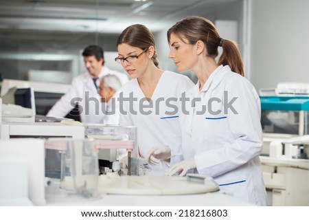 Female technicians operating machine in laboratory