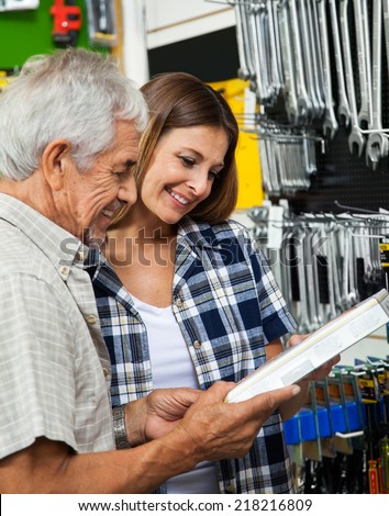 Happy father and daughter holding tool box in hardware shop