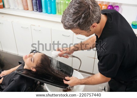 Hairdresser washing female client's hair in beauty parlor