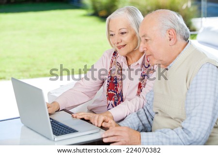 Senior couple using laptop while sitting at nursing home porch