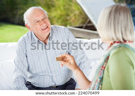 Senior couple talking while playing dominoes at nursing home