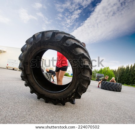 Female athlete flipping large tractor tire outdoors