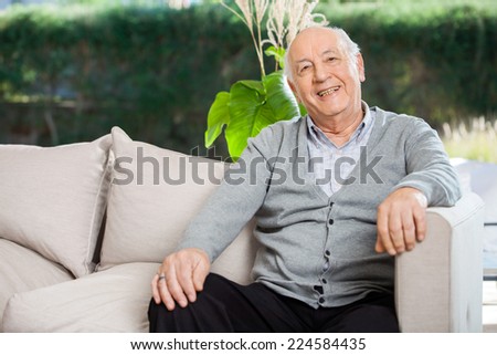 Portrait of happy senior man sitting on couch at nursing home porch