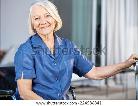 Portrait of happy senior woman sitting on wheelchair at nursing home yard