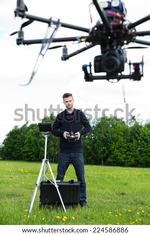 Male engineer with remote control flying surveillance drone in park