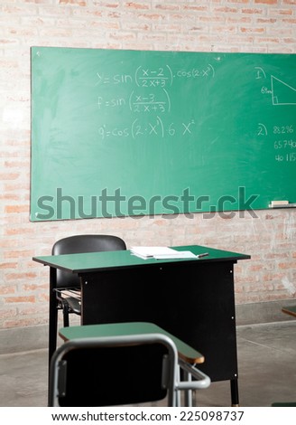 View of empty classroom with greenboard and furniture