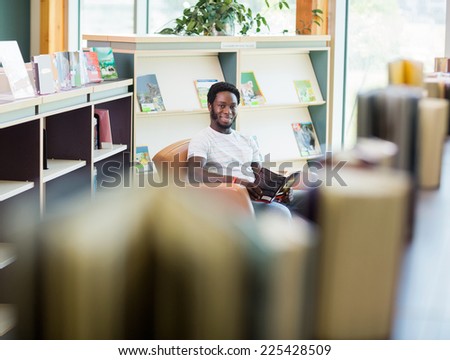 Portrait of smiling male student reading book in library