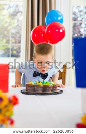 Boy blowing candles on birthday cake at home