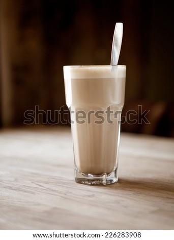 Latte in rustic restaurant on wooden table with spoon