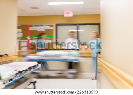 Blurred motion of doctor and nurses with stretcher in hospital corridor