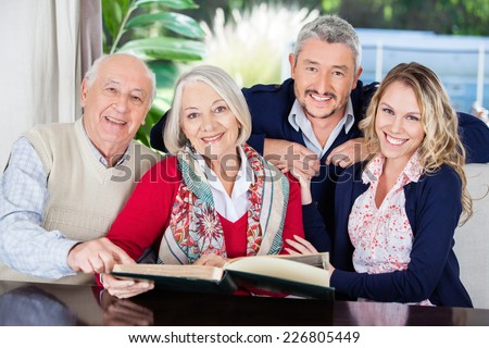 Portrait of happy grandparents and grandchildren with book in nursing home