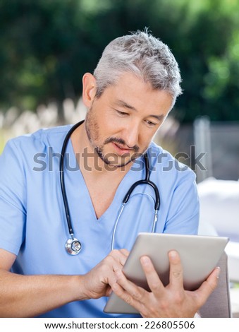 Male caretaker using tablet PC at nursing home