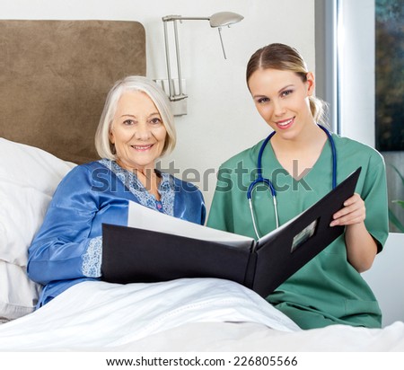 Portrait of female nurse and senior woman with medical reports in bedroom at nursing home