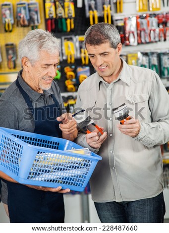 Senior salesperson assisting customer in buying pliers at hardware store
