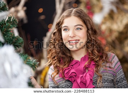 Beautiful young woman smiling while looking away in Christmas store