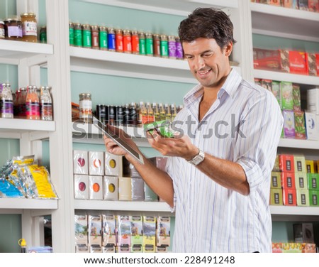 Happy mid adult man looking at product while holding digital tablet in store