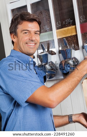 Portrait of male customer standing by coffee vending machine in supermarket