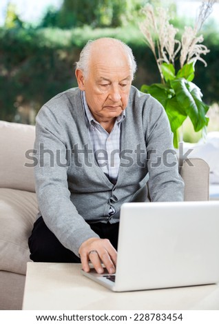 Senior man using laptop while sitting on couch at nursing home porch