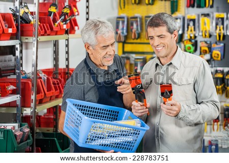 Senior salesman assisting customer in buying pliers at hardware store