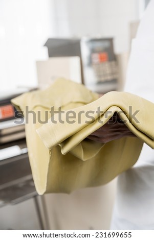 Cropped image of male chef holding spaghetti pasta sheet at commercial kitchen