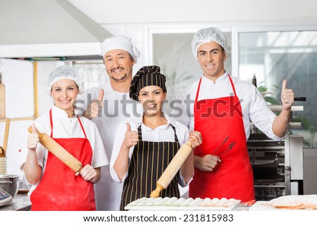 Portrait of confident chef team gesturing thumbsup together in commercial kitchen
