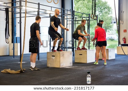 Group of athletes practicing box jumps at gym