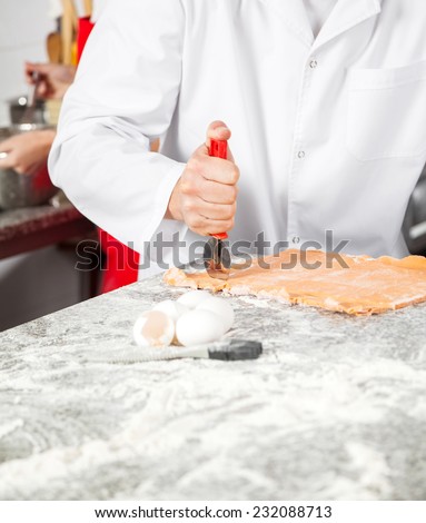 Midsection of chef cutting ravioli pasta at messy commercial kitchen counter
