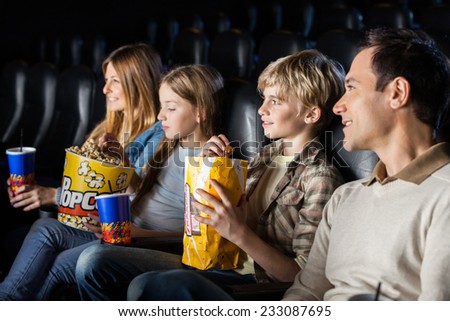 Family having snacks while watching movie in cinema theater