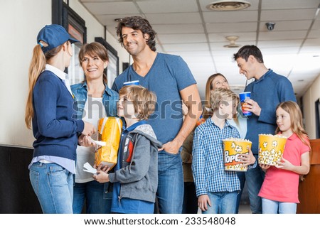 Female worker with families holding snacks at cinema