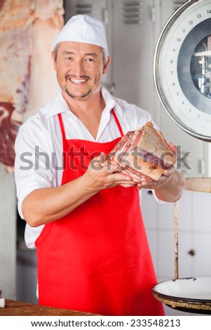 Portrait of confident male butcher showing meat in butchery