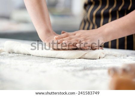 Midsection of chef pressing dough at messy counter in commercial kitchen