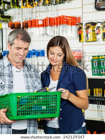 Couple carrying basket full of tools in hardware store