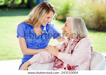 Affectionate granddaughter and grandmother looking at each other on nursing home porch