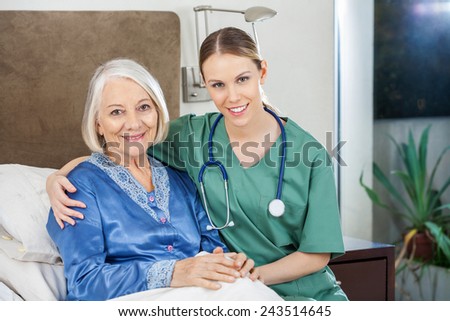 Portrait of happy female caretaker with arm around senior woman at nursing home
