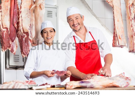 Portrait of happy male and female butchers working at counter in butchery