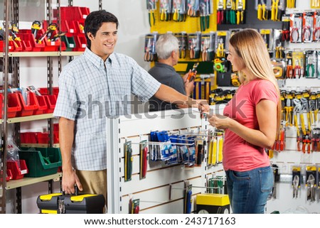 Smiling couple looking at each other while choosing tools in hardware store
