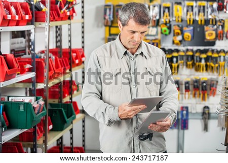 Mature male customer analyzing product through digital tablet in hardware store