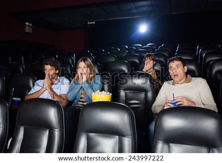 Shocked people watching film in movie theater