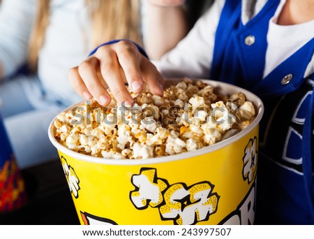Midsection of girl eating popcorn in cinema theater