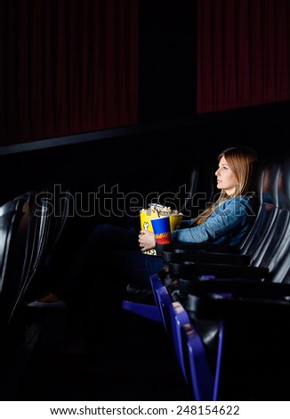 Full length of woman with snacks watching movie at cinema theater