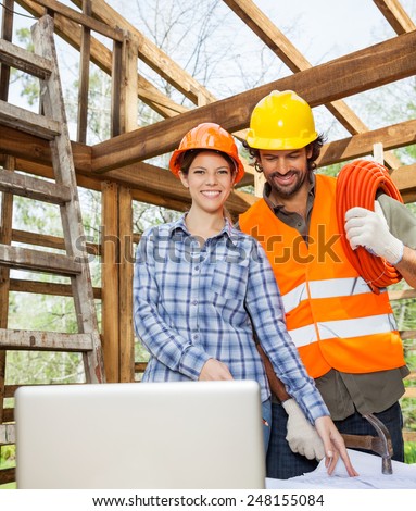 Portrait of smiling female architect working with construction worker at site