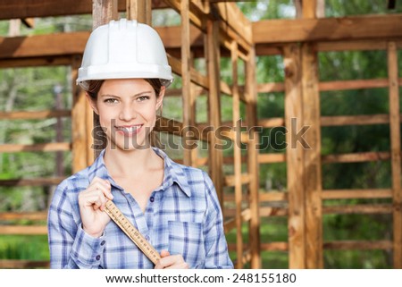 Portrait of happy female construction worker holding measuring tape at site